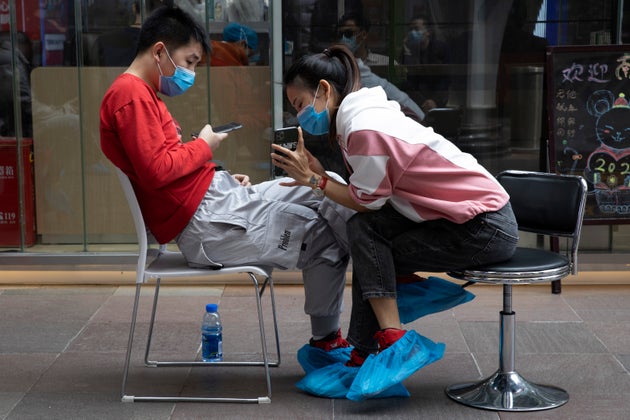 A man and woman sit together outside a blood donation center in Wuhan on Tuesday, April 7,