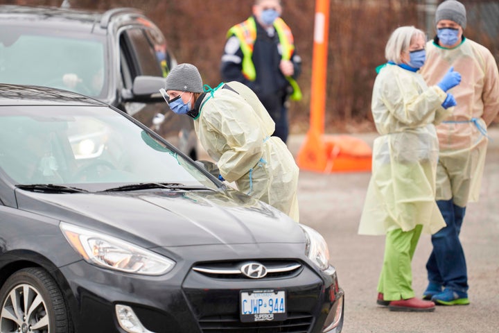 Health care workers speak with patients at a drive-thru Covid-19 assessment centre in London, Ont., on March 17, 2020.
