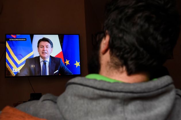 TURIN, ITALY - 2020/03/16: A man watches Italian Prime Minister Giuseppe Conte on TV announcing new economic...