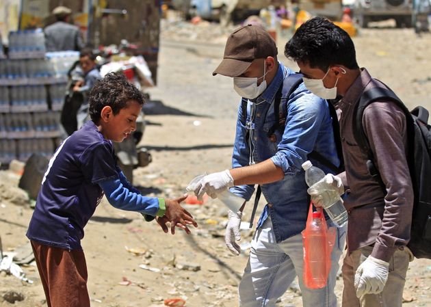 A volunteer in Sanaa, Yemen, sprays disinfectant on the hands of a boy in the one of the city's poor...