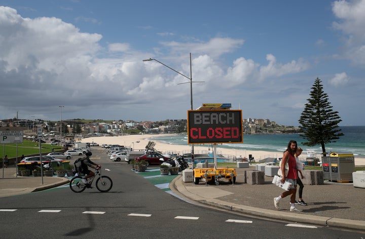 People walk past a "Beach Closed" sign at Bondi Beach, as the beach remains closed to prevent the spread of the coronavirus disease (COVID-19), in Sydney, Australia April 1, 2020. REUTERS/Loren Elliott