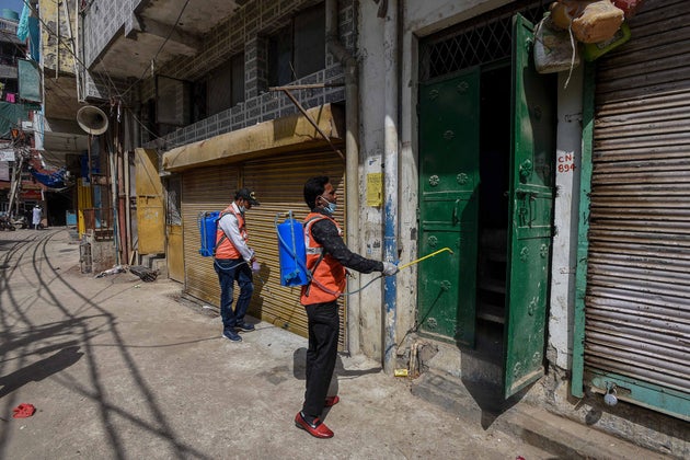 A municipal health worker sprays disinfectant while sanitising shops and homes at Gandhi Park at Hauz...