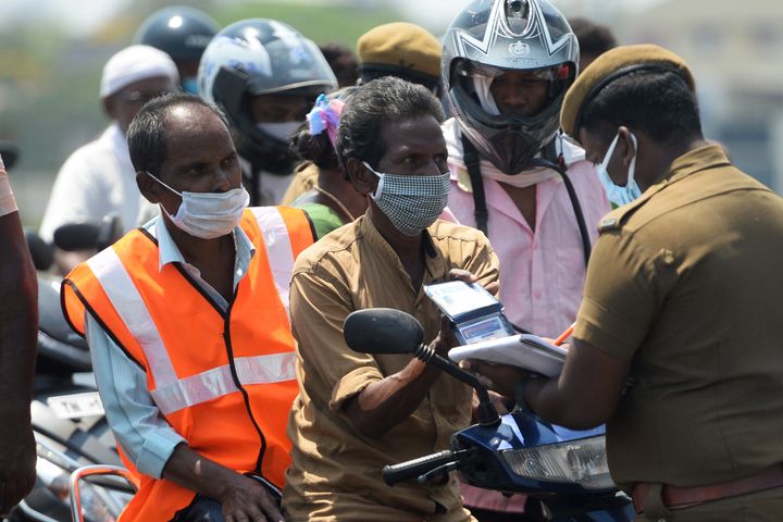 Police check a commuter valid credentials for travel during a government-imposed nationwide lockdown in Chennai on April 1, 2020. 