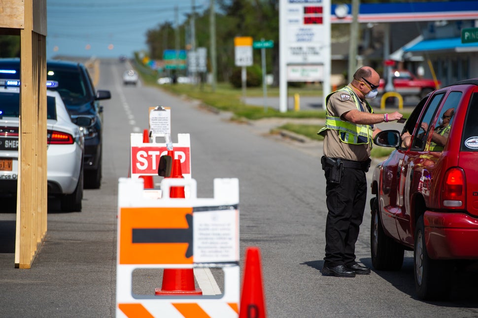 An officer with the Dare County Sheriff's Office inspects the identification of a driver entering the Outer Banks. This coron