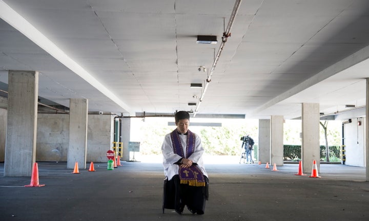 Assistant Pastor at St. Patrick's Parish Father Felix Min waits for a car to pull up during a drive-thru confession in a parking garage at the church in Vancouver on April 8, 2020.