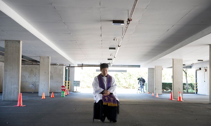 Assistant Pastor at St. Patrick's Parish Father Felix Min waits for a car to pull up during a drive-thru confession in a parking garage at the church in Vancouver on April 8, 2020. 