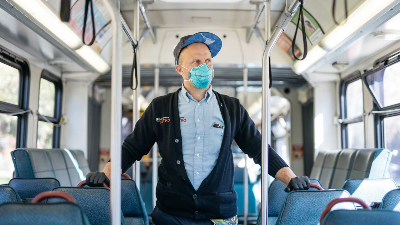 King County Metro bus driver Sam Smith poses for a portrait while on a break in Seattle on April 8, 2020. Smith is still driving amid the novel coronavirus crisis, utilizing a mask the bus service gave him two years ago during a particularly heavy, smoky fire season.