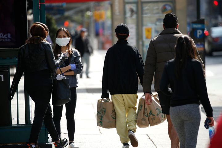 NEW YORK, NY - APRIL 07: A woman wearing a mask looks on as passerby walk on 7th avenue amid the coronavirus pandemic on April 7, 2020 in New York City. COVID-19 has spread to most countries around the world, claiming over 80,000 lives with over 1.4 million infections. (Photo by John Lamparski/Getty Images)