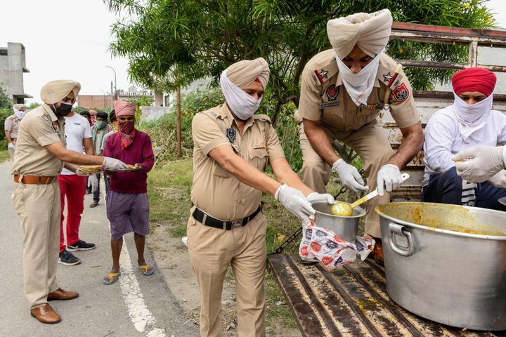 Police personnel distribute food to people during the lockdown, on the outskirts of Amritsar on April 9, 2020.