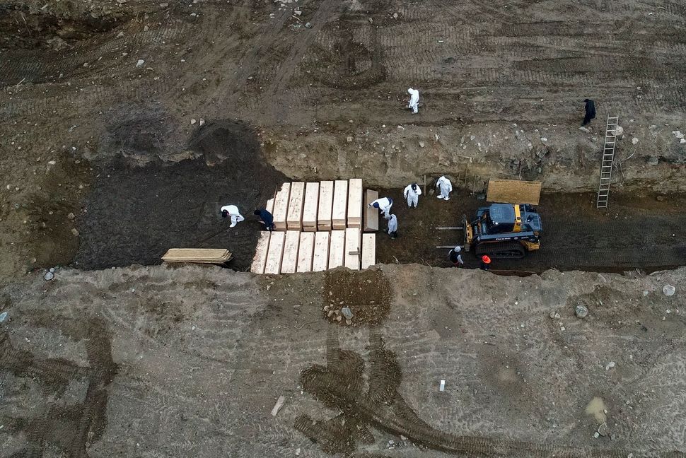 Workers wearing personal protective equipment bury bodies in a trench on Hart Island, which is in the Bronx borough of New Yo