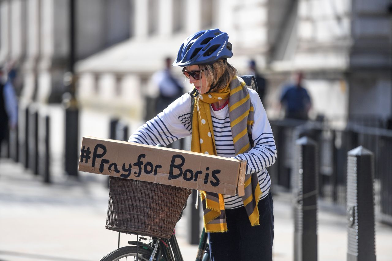 A cyclist with a sign reading '#PrayforBoris' rides through Westminster.