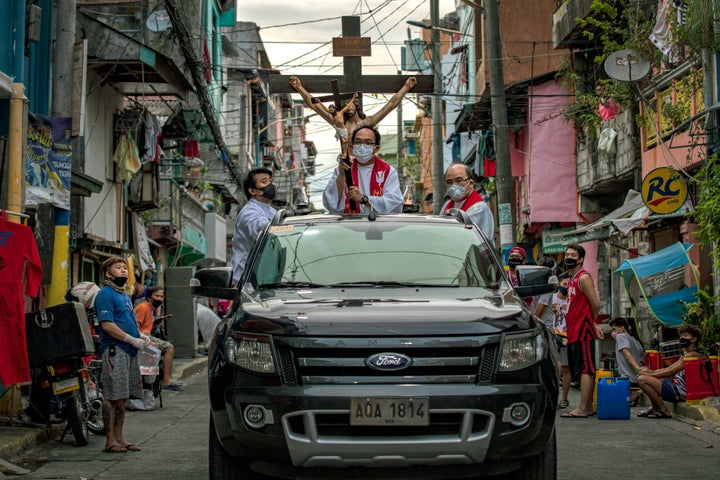 Catholic priests bless residents quarantined in their homes as part of Good Friday commemorations, amid a government lockdown