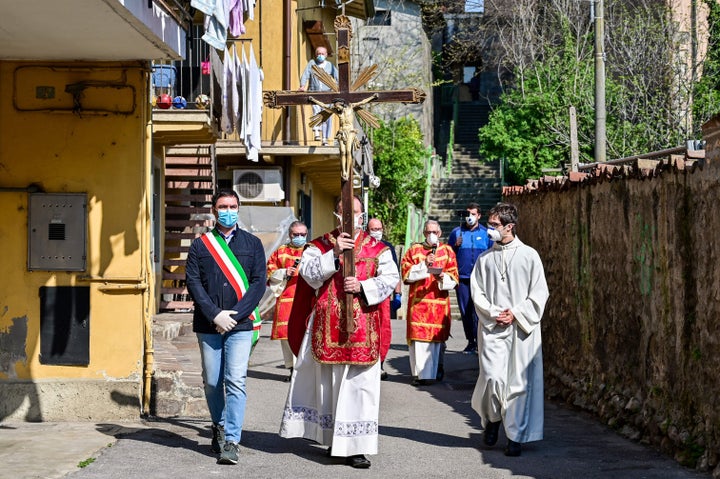 Rev. Giovanni Cominardi (center), priest of Santa Maria Assunta church in Pontoglio, Italy, and Pontoglio's mayor, Alessandro Seghezzi, (left) wear face masks during a Good Friday procession on April 10, 2020.