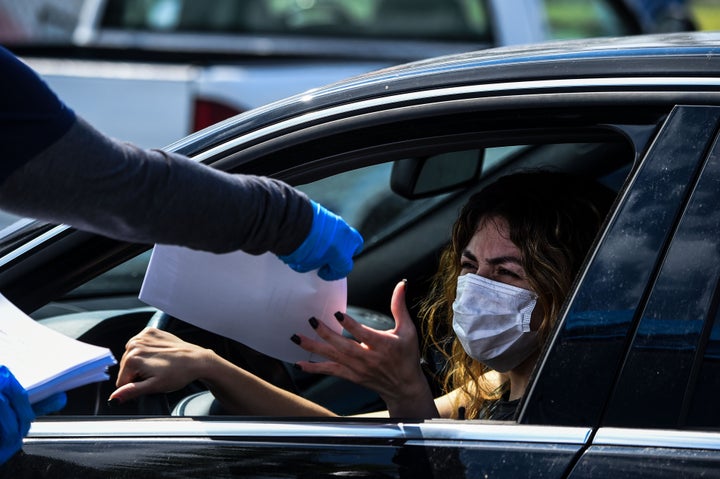 A woman collects unemployment forms at a drive-through collection point outside John F. Kennedy Library in Hialeah on April 8.