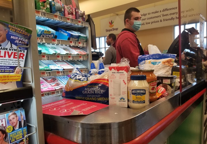 A masked cashier rings up purchases behind a plexiglass shield at a Stop and Shop grocery store in Queens, New York. 