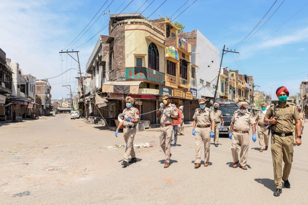 Punjab police personnel wearing facemasks patrol on a deserted street during a government-imposed nationwide...