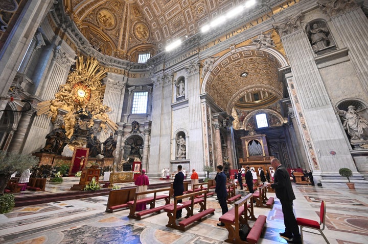 Few faithful attends Pope Francis', small white figure at center, Easter Sunday Mass, inside an empty St. Peter's Basilica at