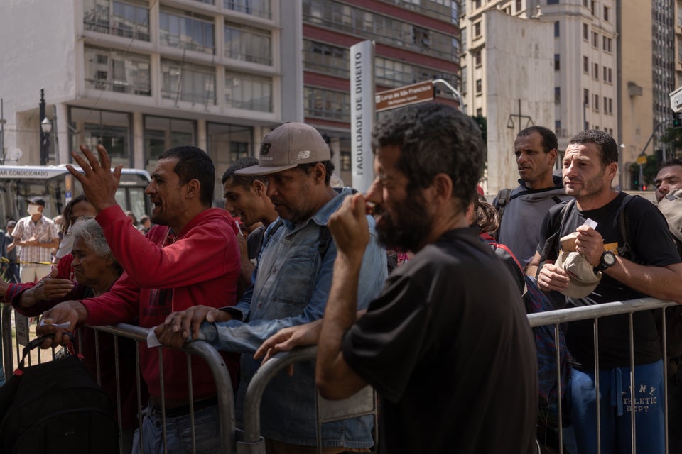 Homeless people queue for food at a medical screening center in São