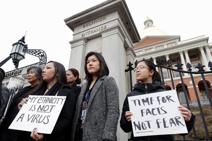 Jessica Wong, of Fall River, Mass., front left, Jenny Chiang, of Medford, Mass., center, and Sheila Vo, of Boston, from the state's Asian American Commission, stand together during a protest, March 12, on the steps of the Statehouse in Boston. Asian American leaders in Massachusetts condemned what they say is racism, fear-mongering and misinformation aimed at Asian communities amid the widening coronavirus pandemic that originated in China.