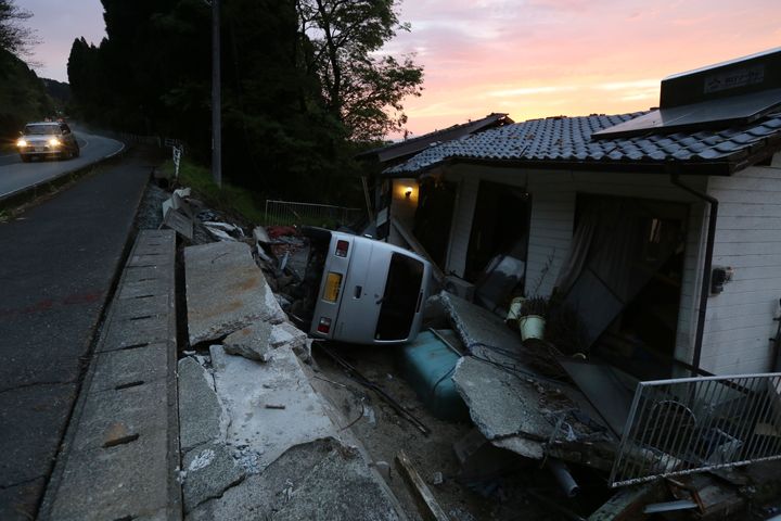地震により、倒壊した家屋と横転した車＝１８日、熊本県西原村 