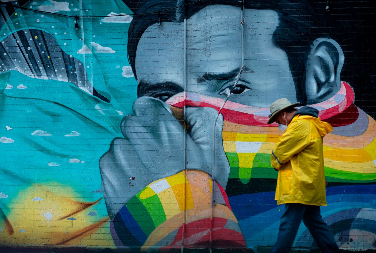 A man wearing a mask passes a mural on April 13, 2020 in New York City.