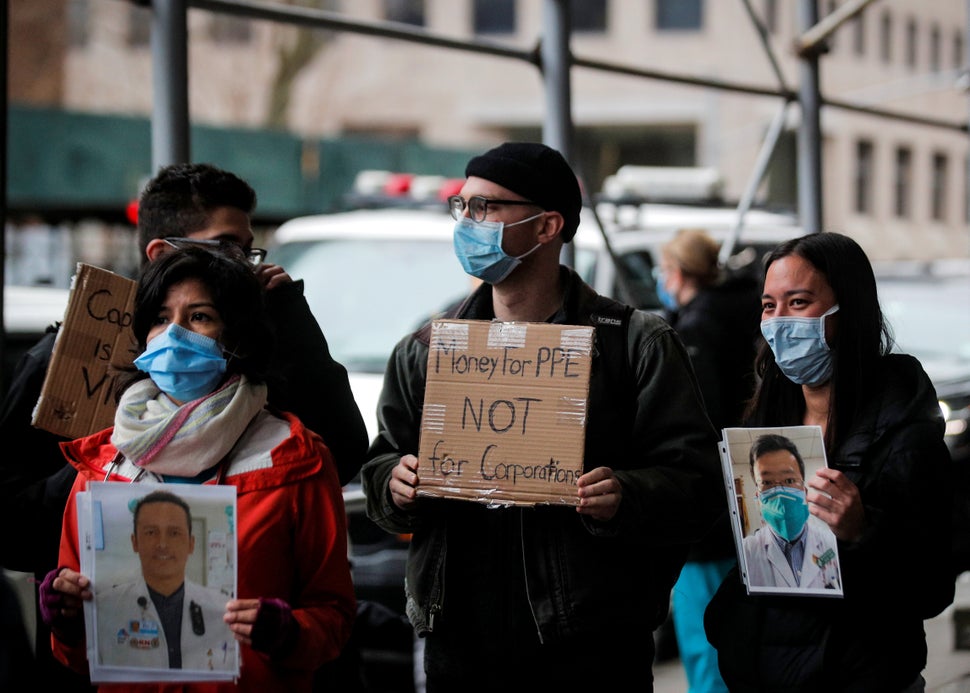 Health care workers at Mount Sinai Hospital hold photos of sick colleagues during a protest demanding critical personal prote