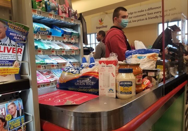 ニューヨーク・クイーンズにあるスーパーマーケット。マスクをした店員が保護シールドの向こうでレジを打つ
