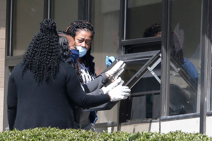 Family members visit a relative through a window at the Canterbury Rehabilitation & Healthcare Center Saturday April 4, 2020, in Richmond, Va. The Center has numerous had Covid-19 cases and deaths.