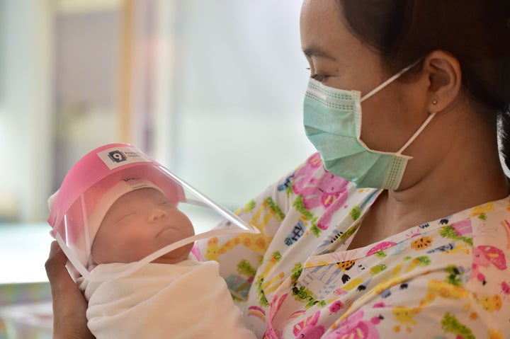 A nurse at Praram 9 Hospital in Bangkok, Thailand, holds a newborn baby wearing a face shield, in an effort to halt the spread of the COVID-19 coronavirus.