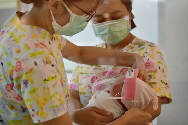 Nurses put a face shield on a newborn baby at Praram 9 Hospital in Bangkok on April 9.