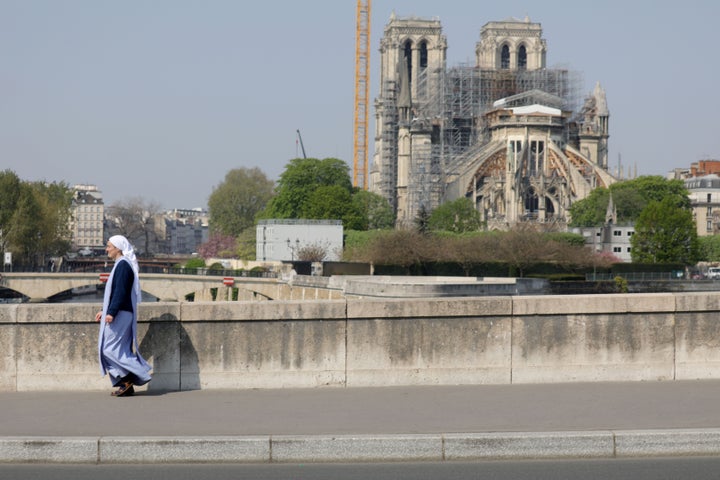 A nun is seen walking on the "De La Tournelle bridge" with Notre Dame Cathedral in the background on April 10, 2020, in Paris.