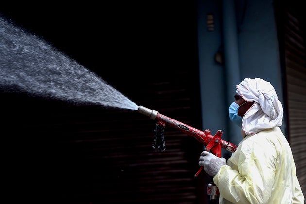 A municipal worker sprays disinfectant solution to sanitise a residential area in Faridabad on April...