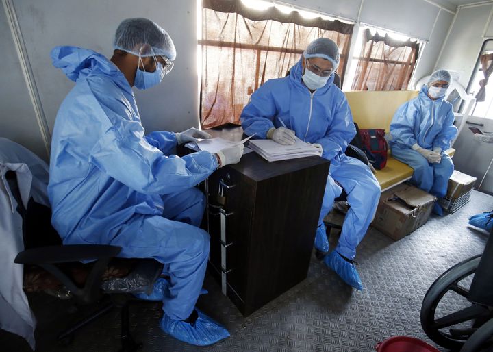 Members of a medical team wearing protective gear work inside a corona mobile testing van in Ahmedabad on April 7, 2020.