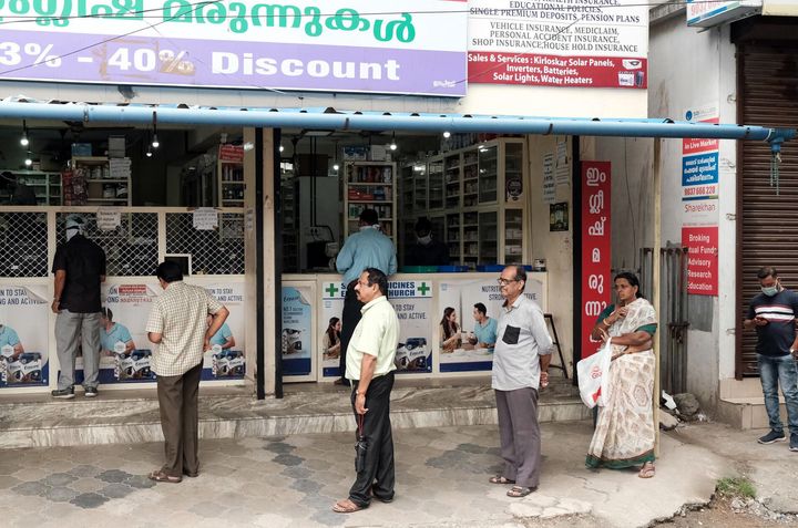 People queue in a line at a pharmacy in Kochi on March 25, 2020.