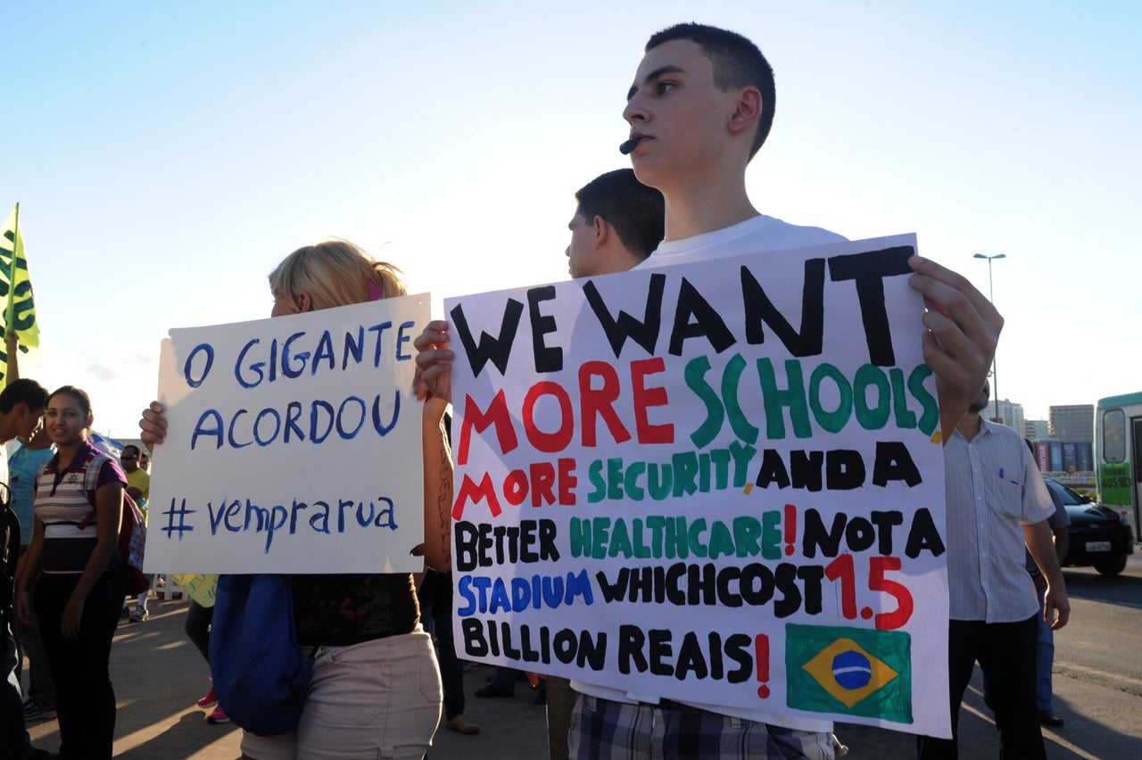 <em>Students hold signs during a protest demanding better public services and criticizing massive government spending on the World Cup. Pinto said he was disappointed by the lack of Afro-Brazilian participation in the World Cup protests, which were largely led by light-skinned, middle-class residents. (Evaristo Sa/Getty Images) <br><br><em>The reporting for this project was made possible by a Social Justice Reporting for a Global America fellowship from the <a href="http://www.icfj.org/" target="_hplink" role="link" class=" js-entry-link cet-external-link" data-vars-item-name="International Center for Journalists" data-vars-item-type="text" data-vars-unit-name="5e987b43e4b021bb4121be9d" data-vars-unit-type="buzz_body" data-vars-target-content-id="http://www.icfj.org/" data-vars-target-content-type="url" data-vars-type="web_external_link" data-vars-subunit-name="article_body" data-vars-subunit-type="component" data-vars-position-in-subunit="14">International Center for Journalists</a>.</em></em>