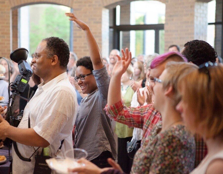 Lauren Jacobs and other models in the "Family Matters" exhibit raise their hands during the opening reception. (Photo by Cary Norton)