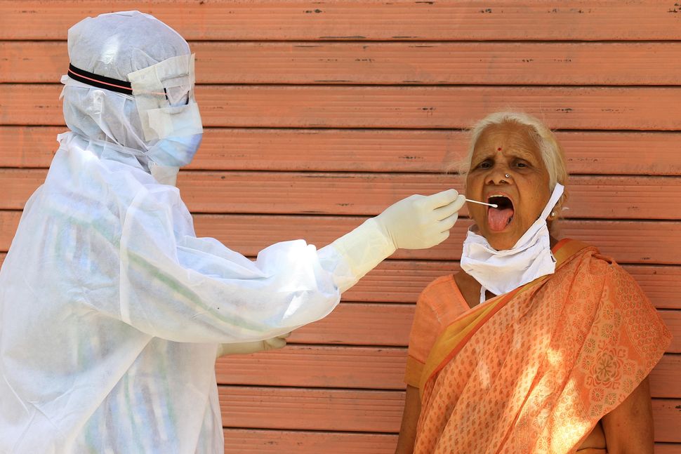 A medic collects a swab sample of an elderly woman during a door-to-door examination of COVID-19 during a curfew imposed in Jaipur, Rajasthan on April 15.