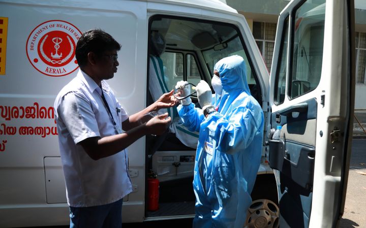 An ambulance driver (R) of Ernakulam medical college puts on gears up with protective apparel as he prepares before going to pick a suspected virus patient, in Kochi on February 4, 2020.