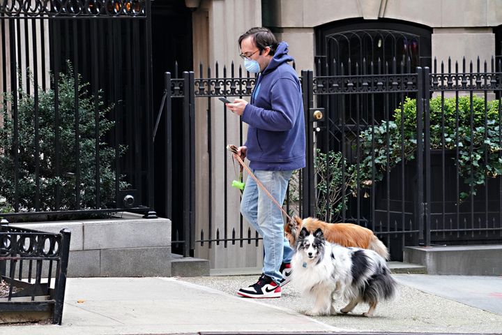 A man wearing a protective mask walks two dogs during the coronavirus pandemic on April 16 in New York City