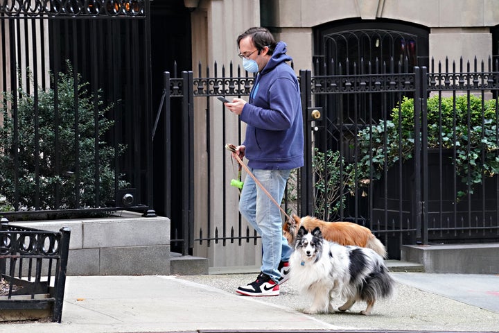 A man wearing a protective mask walks two dogs during the coronavirus pandemic on April 16 in New York City