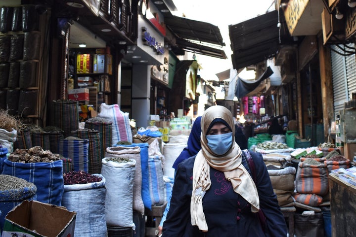 A woman walks through an Al Azhar district street market where people usually buy spices and herbs to prepare for R