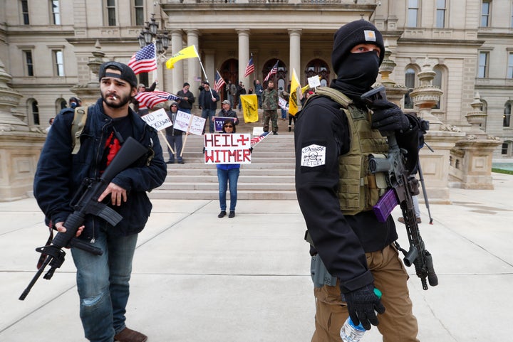 Protesters tote weapons near the steps of the Michigan State Capitol in Lansing on Wednesday to protest social distancing reg