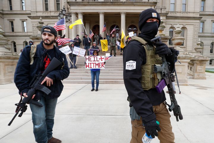 Protesters carry rifles near the steps of the Michigan State Capitol in Lansing on April 15. Flag-waving, honking protesters drove past the Capitol on Wednesday to demonstrate against Gov. Gretchen Whitmer's social distancing measures to slow the spread of the coronavirus.