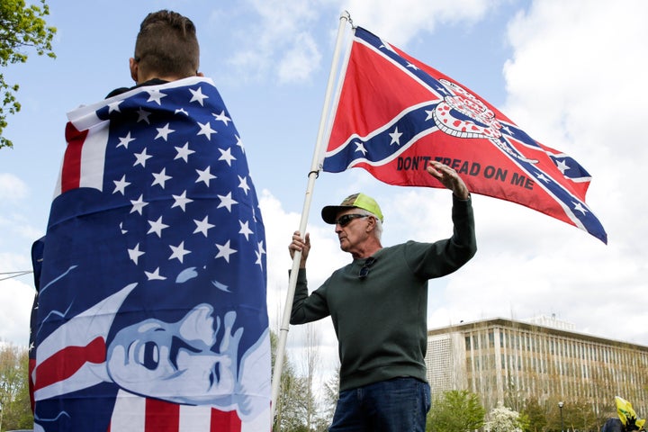 Keith Weber of Centralia, Washington holds a flag that combines a Gadsden flag from the American Revolution with a Confederate flag from the American Civil War as he talks to protesters holding flags with US President Donald Trump on them as people demonstrate against Washington state's stay-home order at the state capitol in Olympia, Washington, on April 19, 2020. - Hundreds protested on April 18 in cities across America against coronavirus-related lockdowns -- with encouragement from President Donald Trump -- as resentment grows against the crippling economic cost of confinement. (Photo by Jason Redmond / AFP) (Photo by JASON REDMOND/AFP via Getty Images)