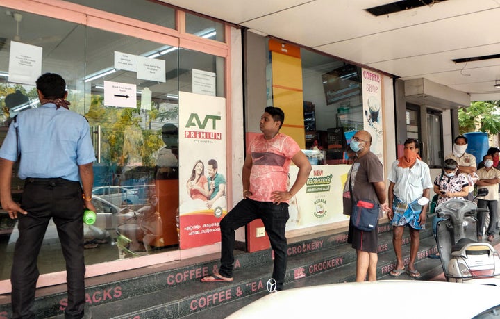 People wait at an ATM counter to withdraw money during the lockdown due to the COVID-19 outbreak in Kochi, March 30, 2020.