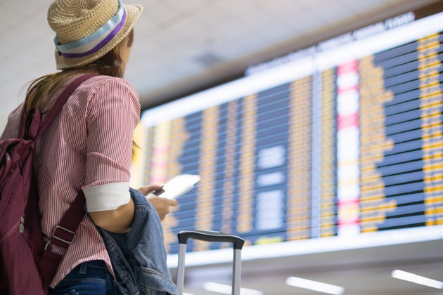 Young woman checking for the flight schedule on time board at