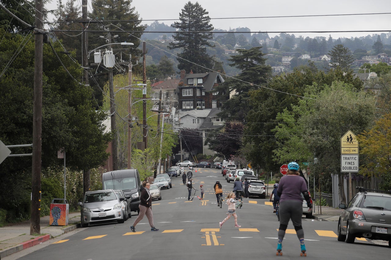 People walk and ride bicycles and scooters on 42nd Street in Oakland, California. The road has been closed to traffic to make it easier for people to socially distance.