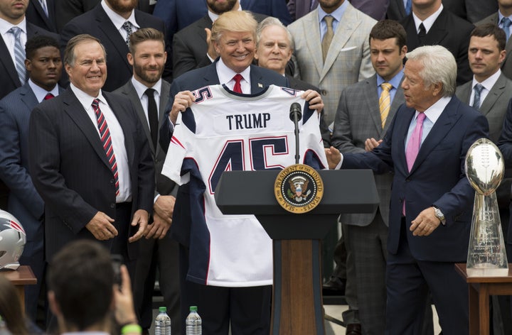 President Donald Trump holds a jersey given to him by New England Patriots owner Robert Kraft (R) and head coach Bill Belichi