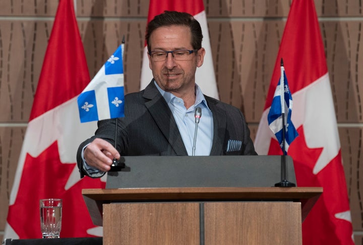 Bloc Leader Yves-Francois Blanchet places Quebec flags on the podium before starting his news conference in Ottawa on April 20, 2020.