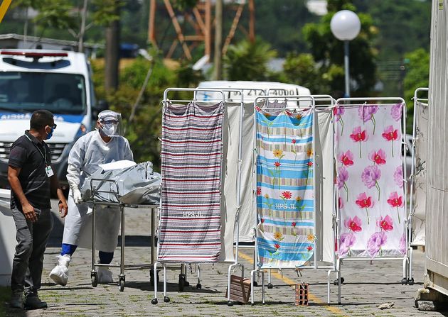 Vítima de coronavírus é transportado por equipes médicas em roupas de proteção para uma área refrigerada do Hospital João Lucio em Manaus. 